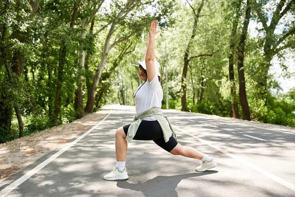 Genç bir kadın ağaçlarla çevrili sakin bir yolda hamlesini yapıyor..