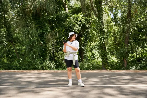 Parlak giyimli kadın ormanda bir patikada güneşli bir yaz gününün tadını çıkarıyor..