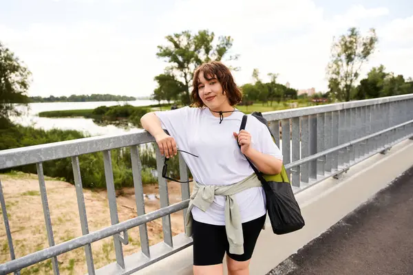 Güzel bir açık havada egzersiz yapmaya hazır, sağlıklı genç bir kadın köprüde duruyor..
