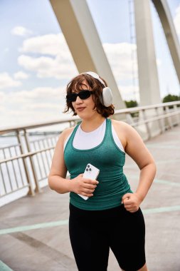 Formda genç bir kadın liman köprüsü boyunca koşar, temiz havada çalışmanın tadını çıkarır..