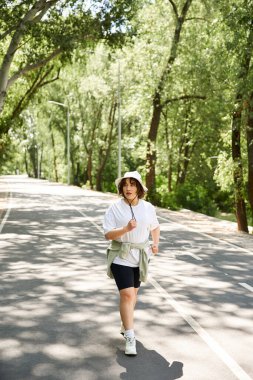 Sağlıklı genç bir kadın ağaçlarla kaplı, huzurlu bir yolda koşuyor, antrenmanının tadını çıkarıyor..