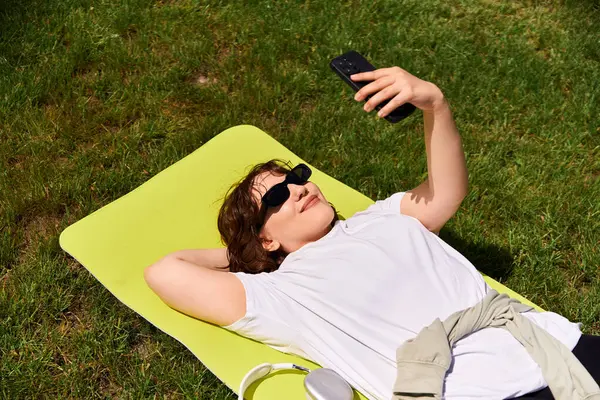 Genç bir kadın güneşli bir günde, açık havada selfie çekerken gülümsüyor..