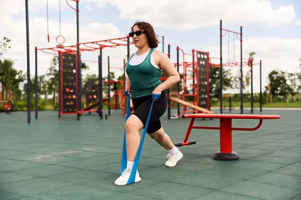 Genç bir kadın enerjik bir şekilde açık hava parkında egzersiz yapıyor..