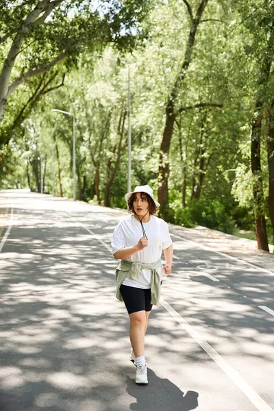 Sağlıklı genç bir kadın ağaçlarla kaplı, huzurlu bir yolda koşuyor, antrenmanının tadını çıkarıyor..