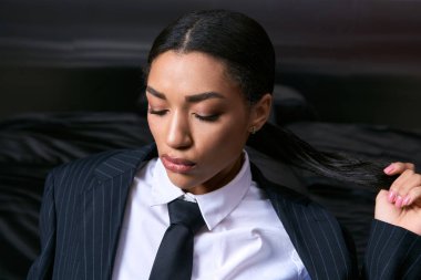 Genç bir kadın şık bir takım elbiseyle, modern bir ortamda poz vererek zarafet saçar..