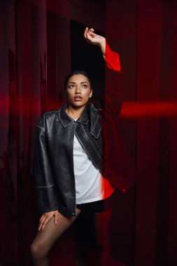 Şık, genç bir kadın dikkat çekici kırmızı bir arka plana karşı şık bir şekilde poz verir..