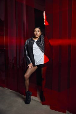 Çarpıcı genç kadın canlı arka planda kendine güvenerek duruyor, zarafet ve tarz saçıyor..