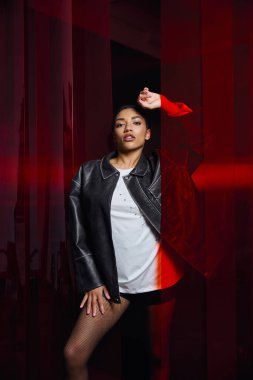 Genç, şık bir kadın, kentsel arkaplanlarda moda kıyafetleriyle poz veriyor..