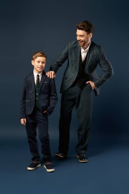 Baba oğluyla neşeli bir anı paylaşıyor, ikisi de şenlikli bir ortam için şık giyinmiş..