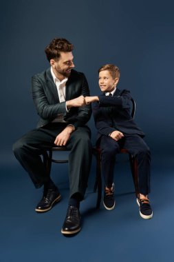 Bir baba ve oğul, kutlama sırasında neşe ve bağı yansıtan neşeli bir yumruk tokuşturur..