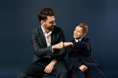 Bir baba ve oğul gülüşür ve yumruk tokuşturur, neşeli bağlarını yakalar..