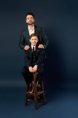 Baba ve oğul neşe dolu bir anı paylaşıyor, zarif giyinmiş, beraberliğin ruhunu kucaklıyor..