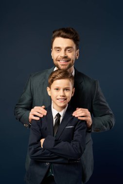 Bir baba ve oğul, Babalar Günü için resmi giysiler içinde gülümseyerek neşeli bir anı paylaşırlar..