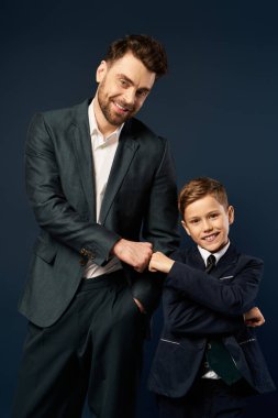 Bir baba ve oğlu, resmi giysiler içinde bağlarını kutlarken keyifle yumruk tokuştururlar..