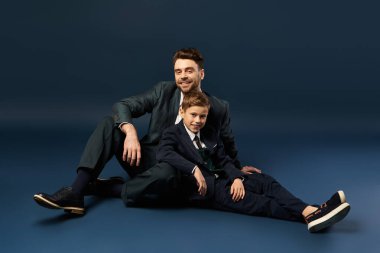 Bir baba ve oğul, özel bir durum için zarif bir şekilde giyinmiş bir birliktelik anını paylaşır..