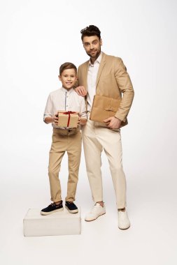 Neşeli bir baba ve oğul birlikte poz verip, Babalar Günü 'nü kalpten hediyelerle kutluyorlar..