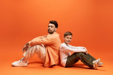 İki gülen şahıs sırt sırta oturup Babalar Günü 'nde neşeli bir anın tadını çıkarıyor..