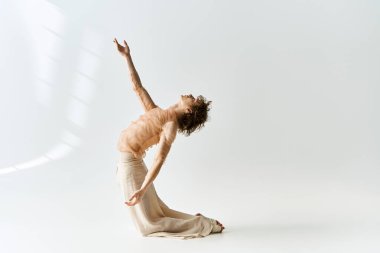 Genç bir adam dans yeteneklerini gri bir stüdyoda sergiliyor. Zarafet ve tutkuyu somutlaştırıyor..