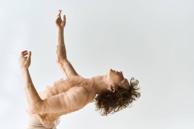 Kıvırcık saçlı genç bir adam dans ederek kendini ifade eder..