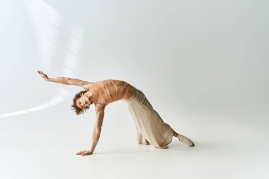 Genç kıvırcık dansçı, minimalist gri arka planda zarafet ve güç sergiliyor..
