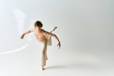 Kıvırcık saçlı bir genç bir stüdyoda zarif bir şekilde dans ederek yeteneğini sergiliyor..