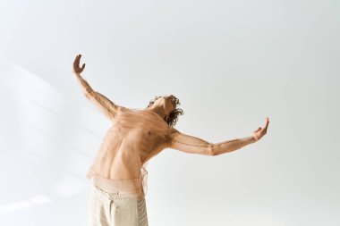 Kıvırcık saçlı dansçı, minimalist gri arkaplan üzerinde sıvı hareketler sergiliyor.