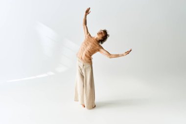 Kıvırcık saçlı genç bir adam modern bir stüdyoda zarif bir dans sergiliyor..