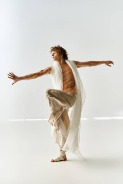 Kıvırcık saçlı dansçı, dans stüdyosunun gri arka planında atletizm ve tutku sergiliyor..