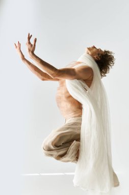 Genç bir adam dans yeteneğini canlı enerjisiyle sergiliyor yumuşak gri bir zemine karşı.