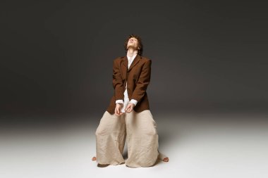 Genç, kıvırcık bir adam modern bir stüdyoda tutkuyla dans ederek yeteneklerini sergiliyor..