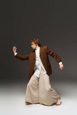 Genç kıvırcık saçlı bir dansçı atletizm ve sanatsal yeteneğini bir stüdyo ortamında sergiliyor..