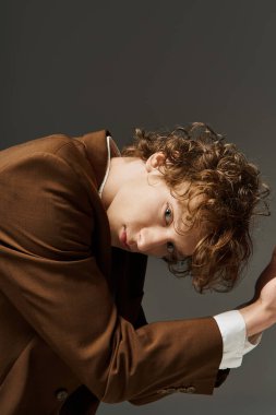 Genç kıvırcık saçlı bir dansçı sanatsal bir stüdyoda dinamik hareketler sergiliyor..