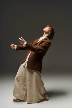 Kıvırcık saçlı genç bir adam minimalist bir stüdyoda akıcı bir şekilde dans ediyor, neşe ve tutku saçıyor..