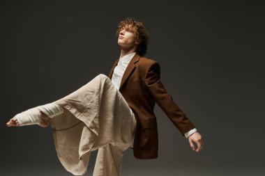 Kıvırcık saçlı dansçı, çağdaş bir stüdyoda hareket ve zarafet gösterir..