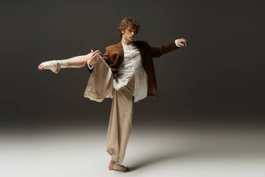 Kıvırcık saçlı genç bir adam dans yeteneklerini stüdyoda sergiliyor, atletizm ve özgüven yayıyor..