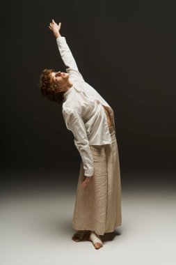 Kıvırcık saçlı genç bir adam zarif bir stüdyoda dans ederken atletizmini sergiliyor..