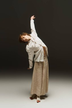 Genç bir kıvırcık adam dans yeteneklerini bir stüdyoda sergiliyor, neşe ve enerjiyi somutlaştırıyor..