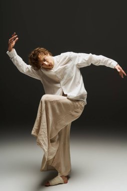 Genç kıvırcık saçlı bir dansçı, çağdaş bir stüdyoda zarif hareketler sergiliyor..