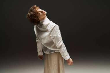 Genç kıvırcık saçlı bir dansçı sanatsal bir stüdyoda akıcılık ve zarafet sergiliyor..