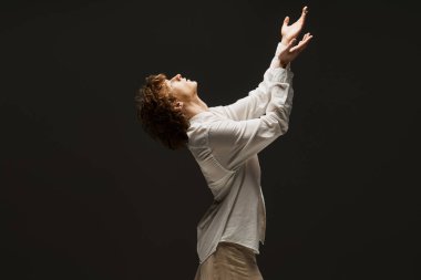 Genç kıvırcık dansçı stüdyoda zarif hareketler sergiliyor. Duyguları ve sanatsallığı somutlaştırıyor..