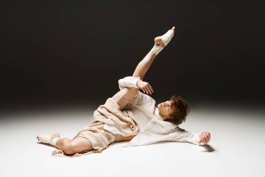 Kıvırcık saçlı, dinamik danslı genç bir adam geniş bir stüdyoda dans ediyor..