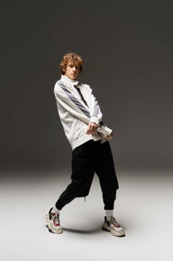 Modern bir stüdyoda, kıvırcık saçlı genç bir adam dans hareketlerini ihtiras ve zarafetle sergiliyor..