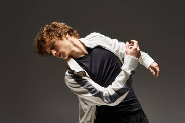 Kıvırcık saçlı bir genç dans yeteneğini dinamik bir stüdyo ortamında sergiliyor..