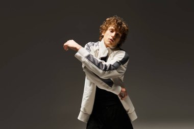 Etkileyici genç adam minimalist bir stüdyo ortamında dans ediyor, yeteneklerini sergiliyor..