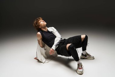 Kıvırcık saçlı genç bir adam dans ederek yeteneğini sergiliyor..