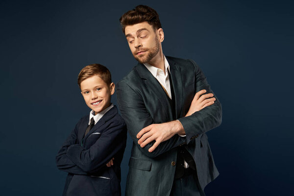 A father and son share a joyful moment, each dressed elegantly, showcasing togetherness and pride.