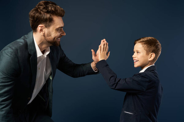 A father and son share a joyful high five, celebrating their bond on Fathers Day 2025.