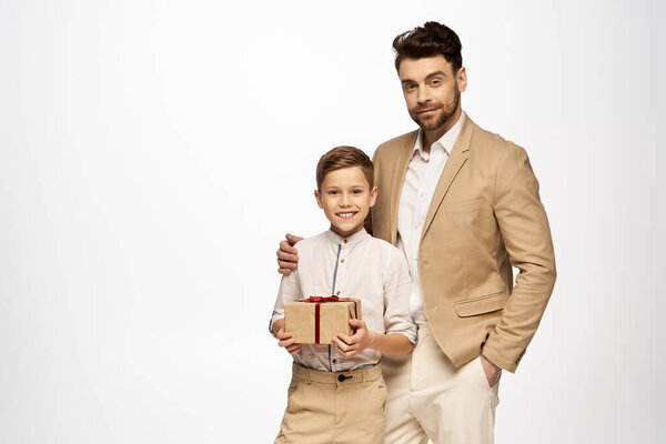 A joyful boy presents a gift to his father, celebrating their bond on Fathers Day 2025.