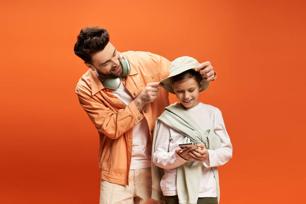 A father lovingly adjusts his sons hat while they share smiles and enjoy their time together.