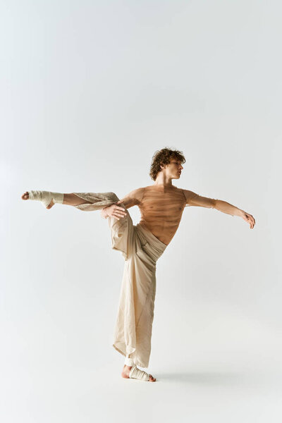 A young curly man dances elegantly in a studio, highlighting his athleticism and passion.